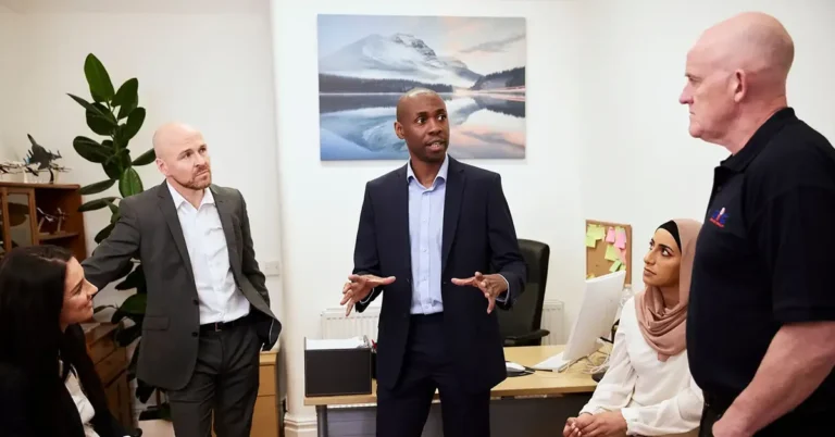 An NIC Local franchisee leads a team meeting in a business office, discussing strategy with staff